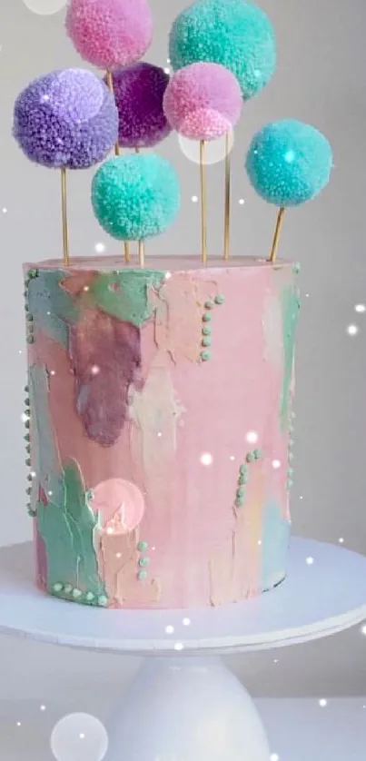 Pastel pink cake with colorful pom-pom decorations on a white stand.