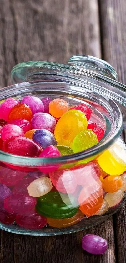 Glass jar filled with colorful candies on a rustic wooden surface.