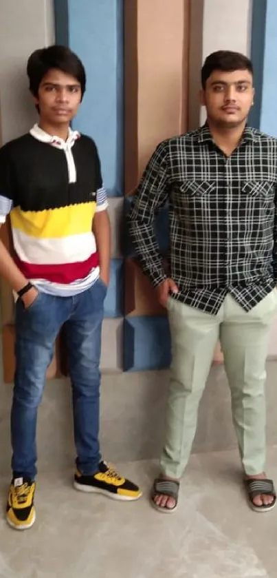 Two young men in stylish casual attire with colorful background.