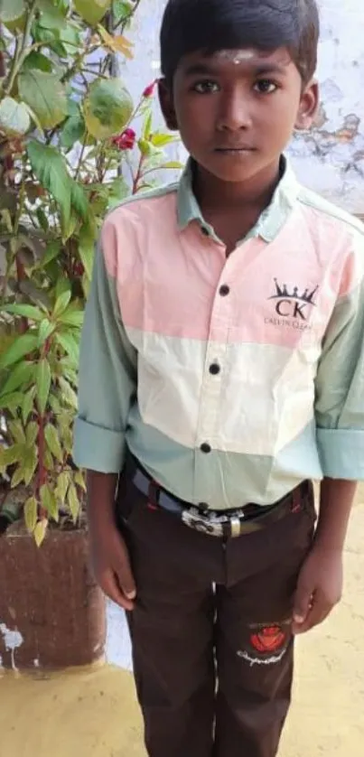 Child standing outdoors with colorful shirt.