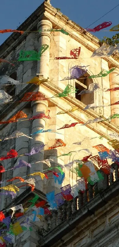 Church tower with colorful flags under blue sky.