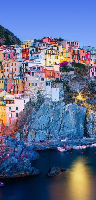 Vibrant coastal town at sunset with colorful buildings and a rocky seaside view.