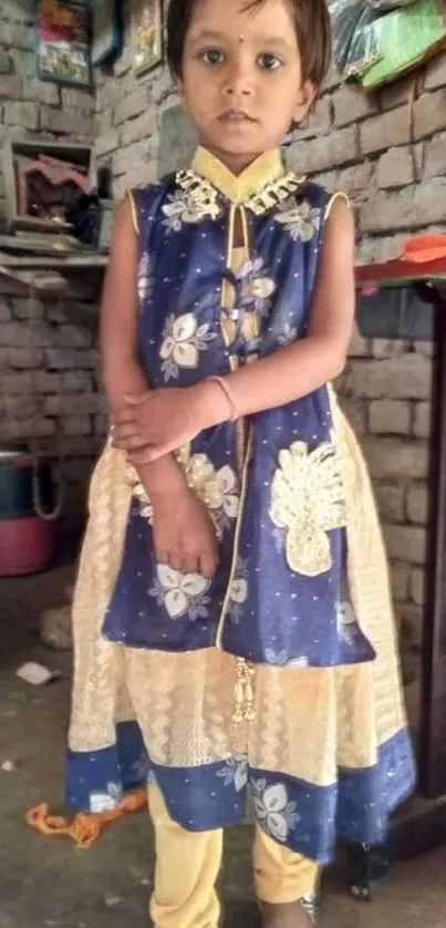 Child in colorful traditional attire against a rustic background.