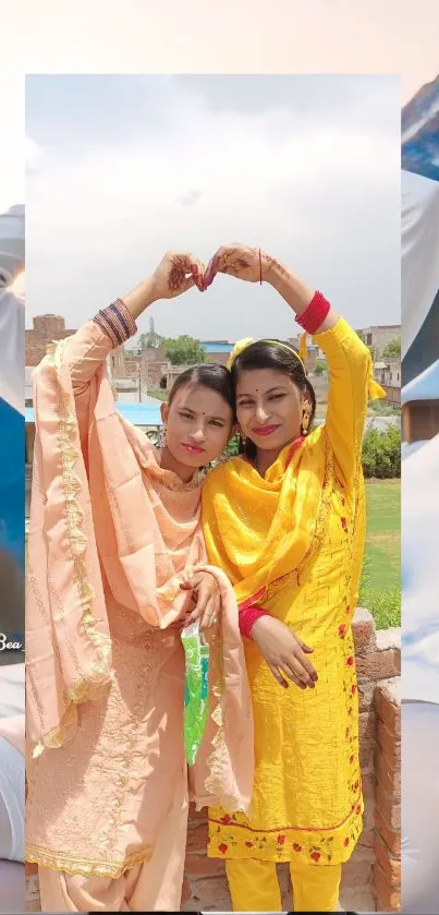 Two women in colorful traditional outfits posing outdoors with a mountainous backdrop.