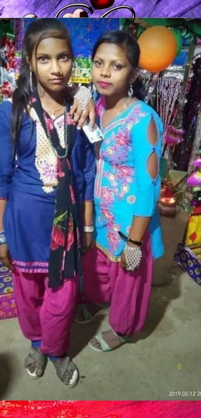 Two women in traditional attire with vibrant colors and cultural background.