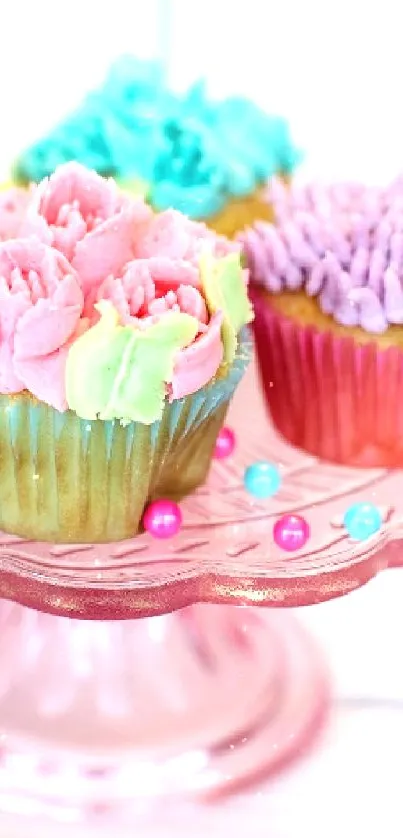 Four colorful decorative cupcakes on a pink stand.