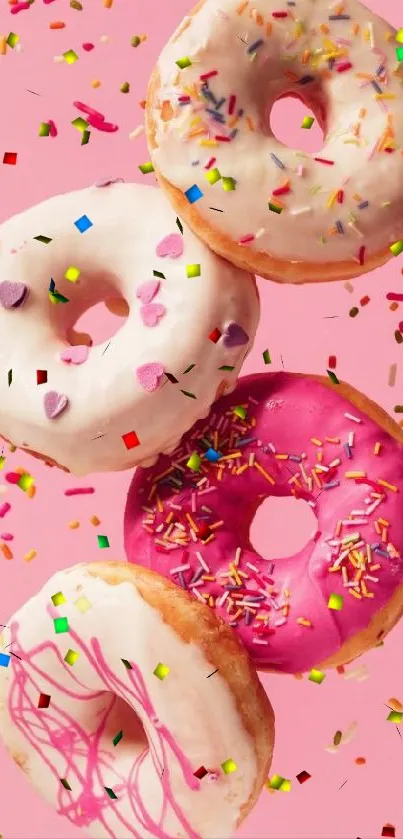 Colorful donuts with sprinkles on a pink background.