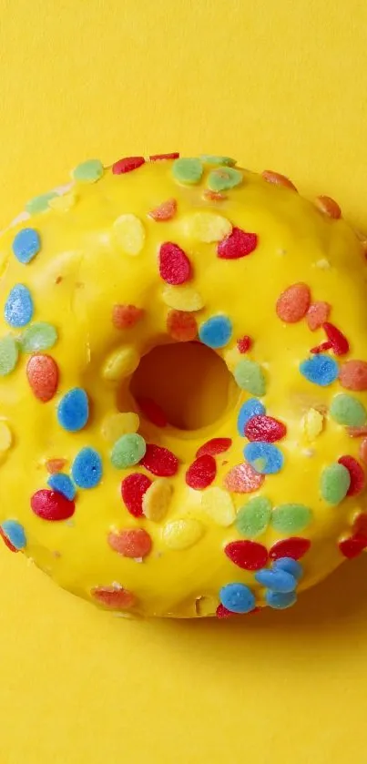 Yellow donut with colorful sprinkles on bright background.