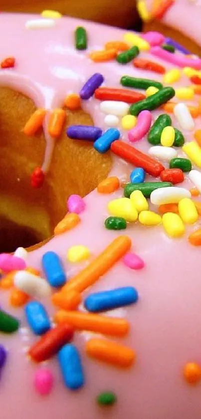 Colorful donut with pink frosting and sprinkles.