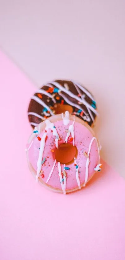 Pink and chocolate donuts with sprinkles on a pastel pink background.