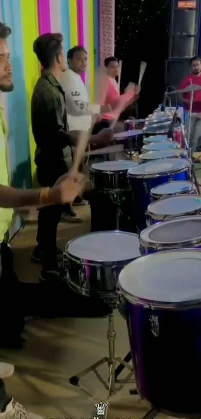 Group of drummers performing energetically with colorful backgrounds.