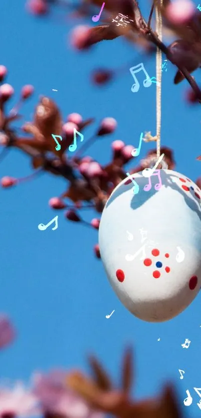 Easter egg hanging from cherry blossom against blue sky.