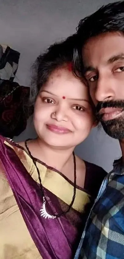 Smiling couple taking a colorful selfie in ethnic attire.