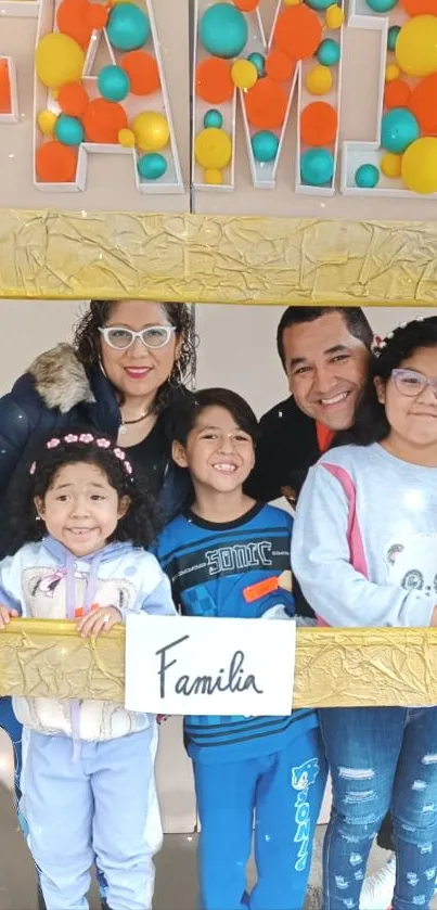 A family posing with colorful balloons and a golden frame.