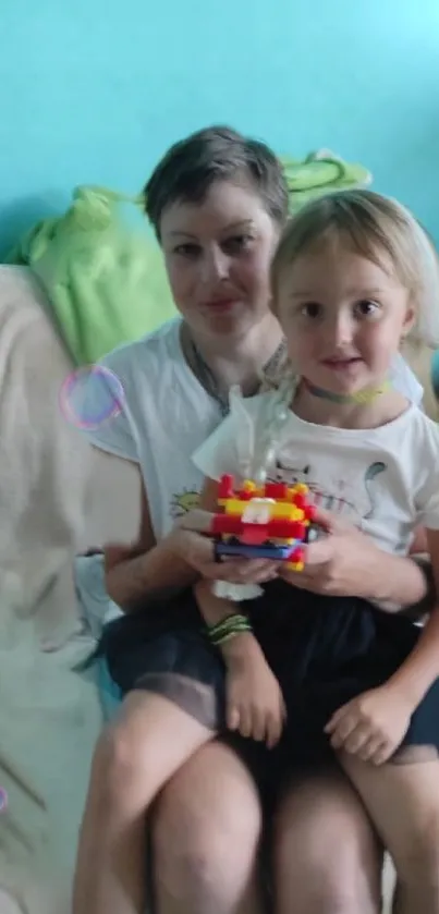 Family sitting together with colorful toys and light blue backdrop.