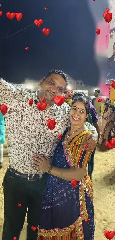 A festive couple at a night event with heart balloons.