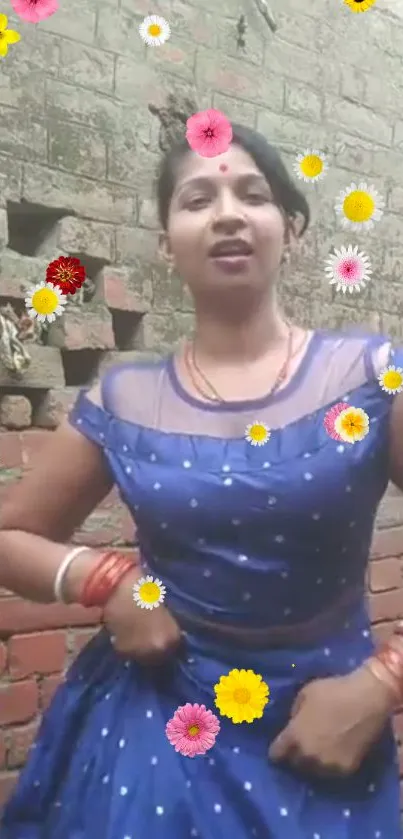 Woman in blue dress with floral overlay against a brick wall.