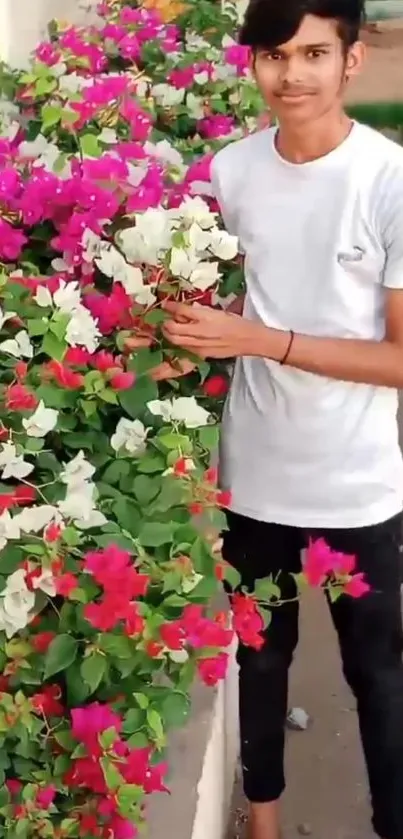 Young person with vibrant pink and white flowers in a lush garden.