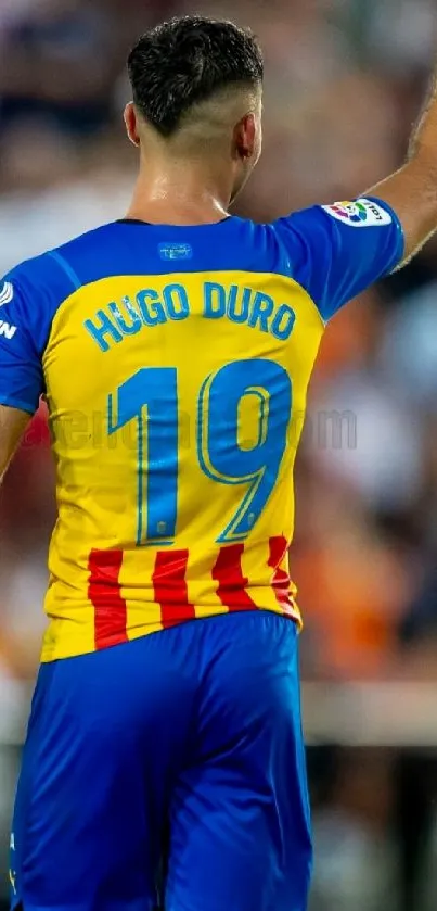 Football player in colorful jersey pointing upwards, wearing number 19.