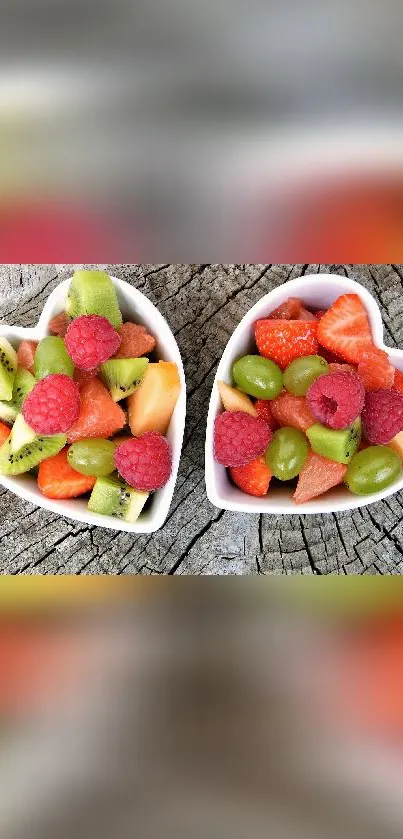 Heart-shaped bowls of colorful fruit on rustic wood background.