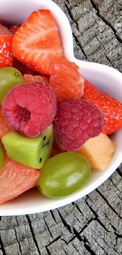 Heart-shaped bowls filled with colorful fruits on rustic wood.