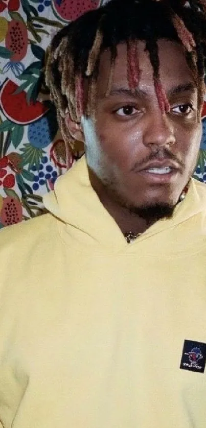 Person in yellow hoodie with fruit background.