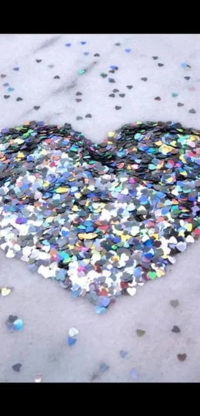 Heart-shaped colorful glitter on light gray background.