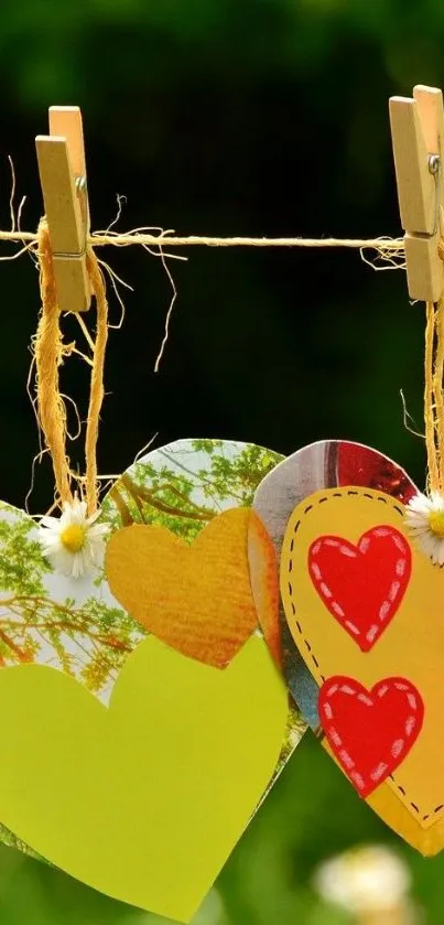 Colorful paper hearts hanging on a clothesline, nature background.