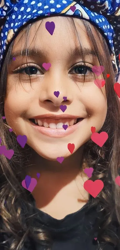 Child wearing blue bandana with vibrant heart decorations.