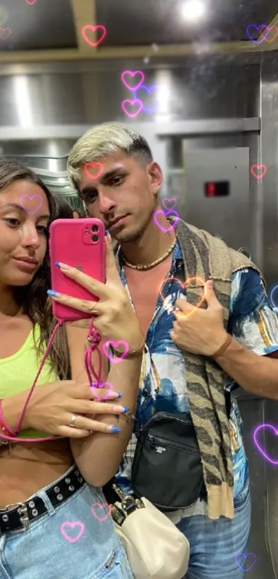Couple in elevator with neon hearts, mirror selfie.