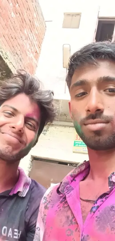 Two friends enjoying Holi with colorful powders on their faces.