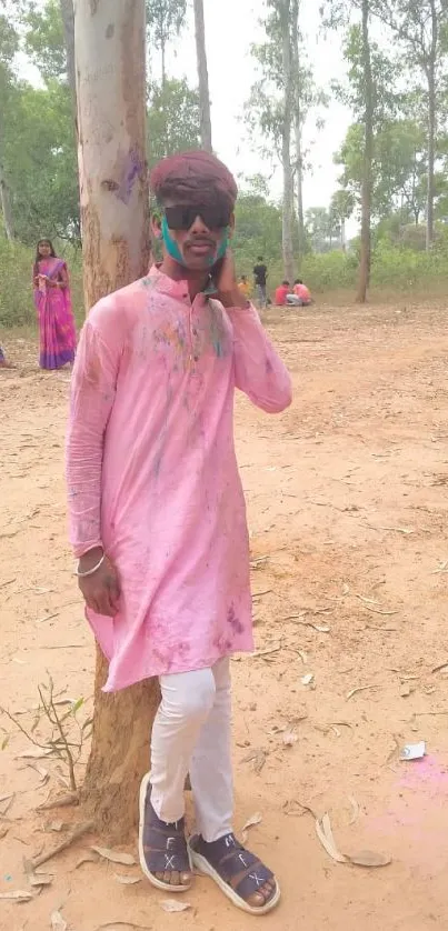 Colorful Holi celebration in nature setting with vibrant attire.