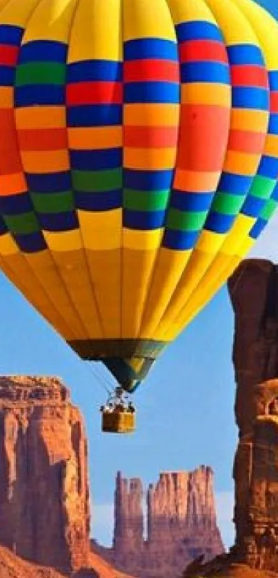 Colorful hot air balloon flying over scenic canyon landscape.