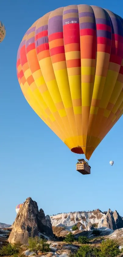 Colorful hot air balloon against a blue sky over rocky terrain.