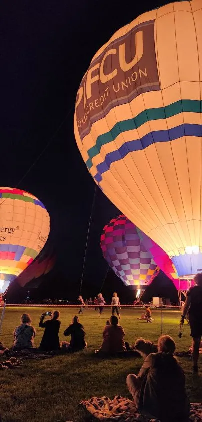 Colorful hot air balloons glowing in the night sky during a festival.