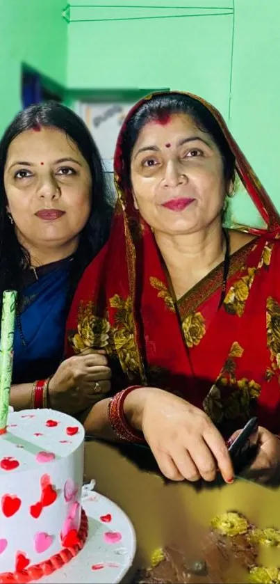 Two women celebrating with a decorated cake.