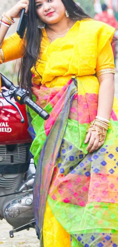 Woman in colorful saree stands beside motorcycle.