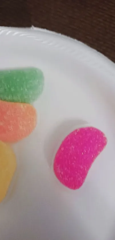 Vibrant jelly candies on white plate wallpaper.