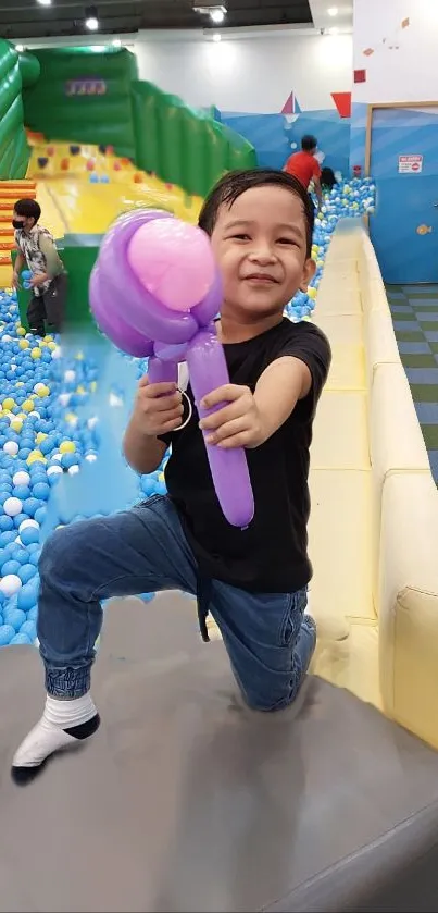 Smiling child playing at colorful indoor playground with balloons.