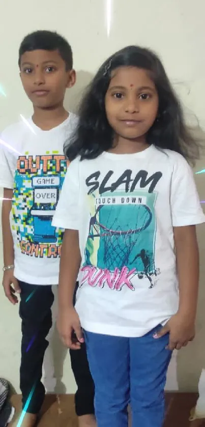 Two kids in colorful themed t-shirts pose cheerfully.