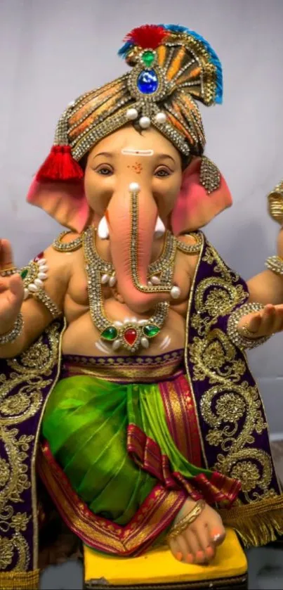 Colorful Lord Ganesha statue in decorative attire on wallpaper.