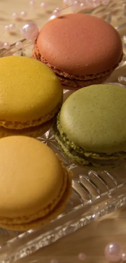 Vibrant macarons on a glass tray with beads around it.