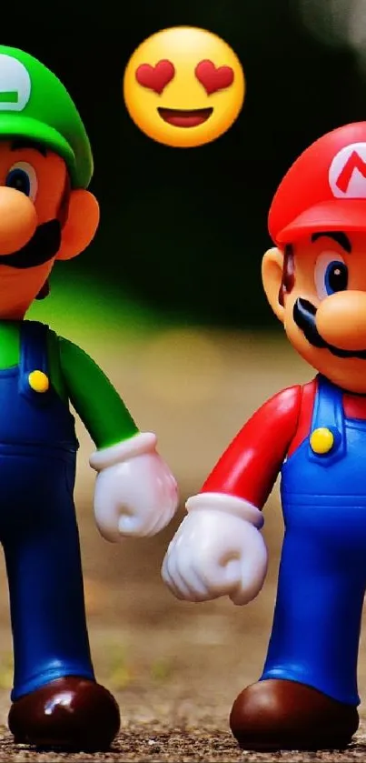 Mario and Luigi toy figures with emoji backdrop on smartphone wallpaper.