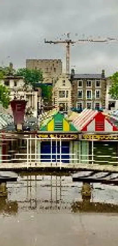 Colorful market stalls reflecting on wet ground under cloudy sky.