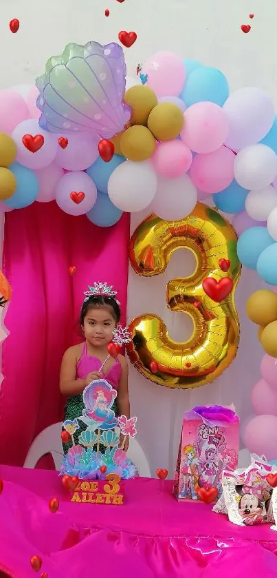 Mermaid-themed birthday party decor with balloons and a bright pink table setting.