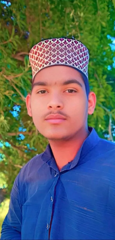 Young man in traditional attire under a green tree.