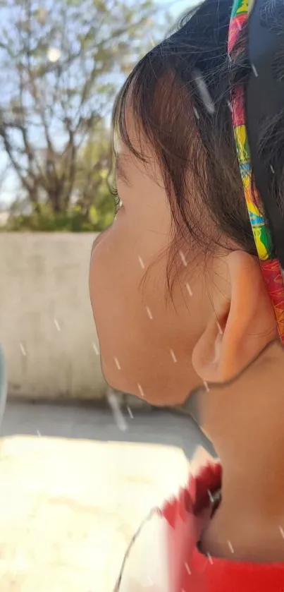 Child with colorful headband in outdoor setting.