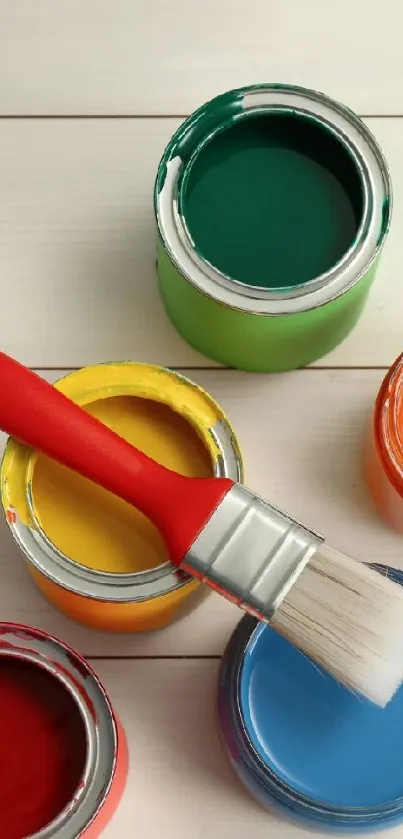 Colorful paint cans with a red brush on wood.