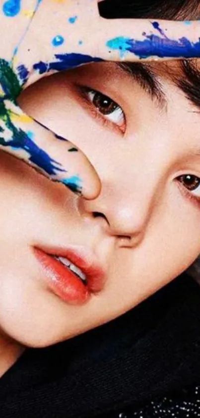 Close-up of a face with a colorful painted hand on a mobile wallpaper.