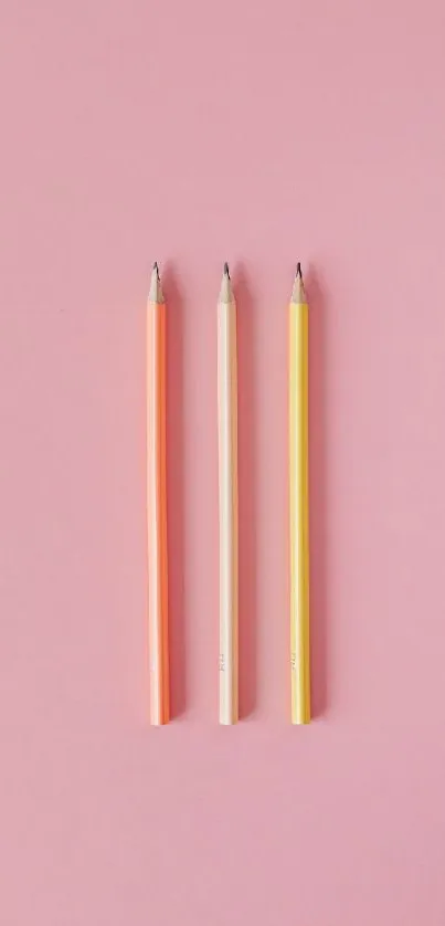 Three colorful pencils on a pink background, perfect as a phone wallpaper.